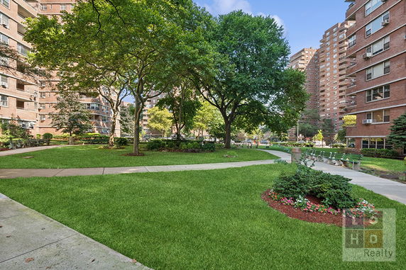 View of trees and pathway surrounded by multiple residential buildings.