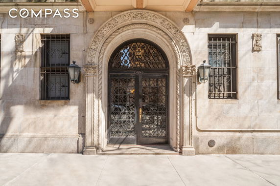 Front view of a building entrance with ornate metal doors and stone carvings.