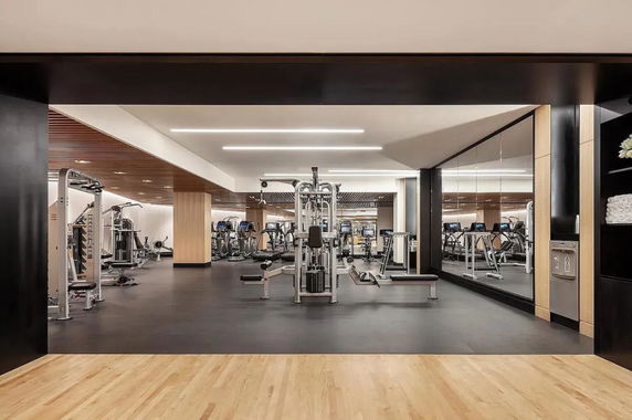 Indoor gym area with exercise equipment and mirrored wall.