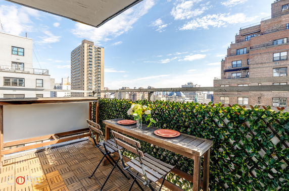 View from a balcony with a dining set overlooking urban buildings.