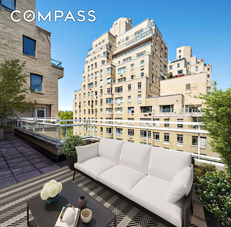 Buildings viewed from a rooftop terrace with outdoor seating area.