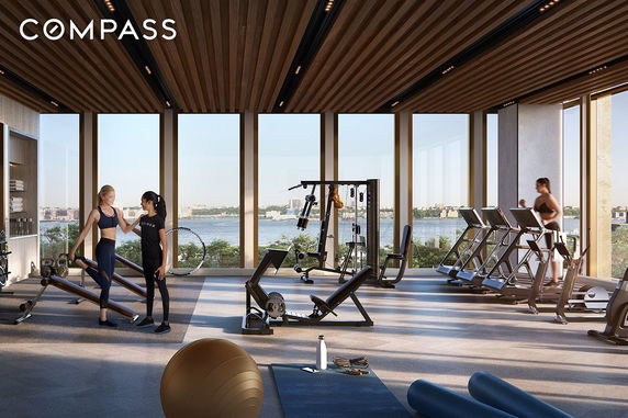 Interior view of a fitness gym with large windows overlooking a river.