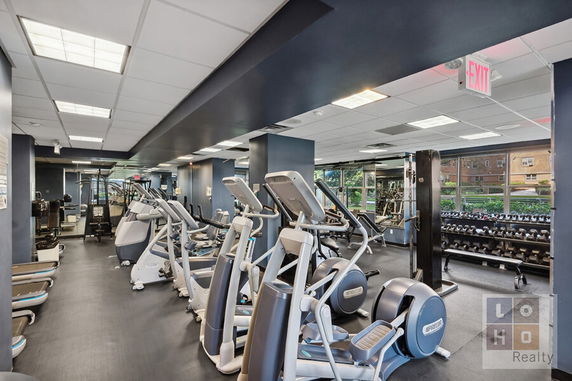 Indoor gym area with various exercise equipment and dumbbells.