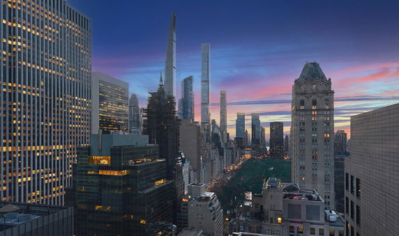 Panoramic view of a city skyline featuring tall buildings with a sunset sky.
