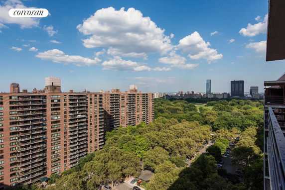 Panoramic view of tall brick apartment buildings and lush green park.