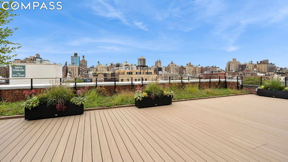 Open rooftop with planters offering a view of city buildings in the background.
