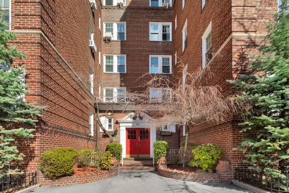 Entrance view of a multi-story brick building with a red door.