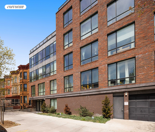 Front view of a multi-story brick building with large windows.