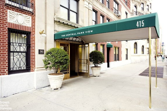 Entrance view of a brick residential building with a green awning extending over the sidewalk.