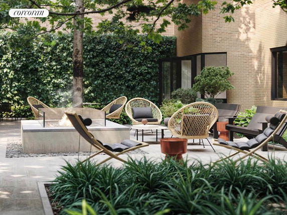 Outdoor seating area with modern chairs and a fire pit, adjacent to a building with brick walls and large windows.