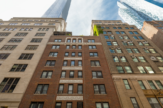 Front view of multi-story brick buildings with a tall skyscraper in the background.