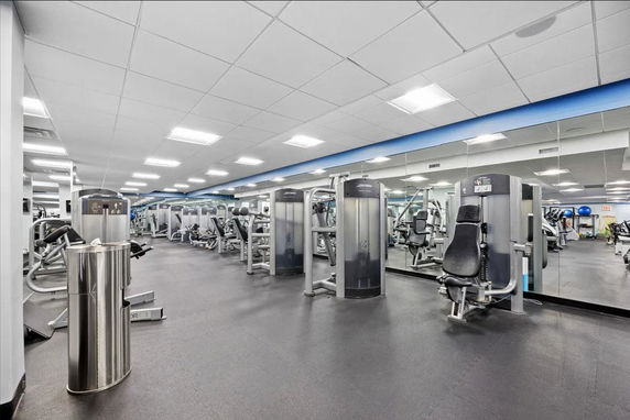 Interior view of a gym with exercise equipment and mirrored walls.