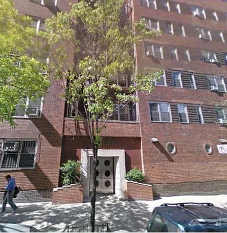 Front view of a multi-story brick apartment building with circular windows and a main entrance.