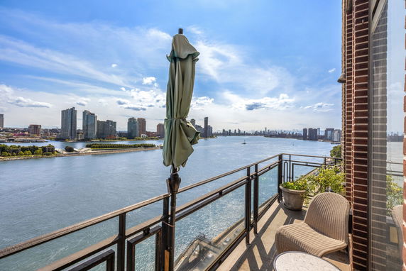 Panoramic view from a balcony overlooking a body of water and city skyline.