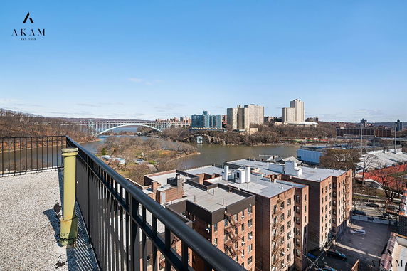 Rooftop view of surrounding buildings and a river visible in the distance.
