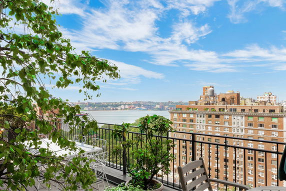 View from a rooftop terrace overlooking a river and city buildings.
