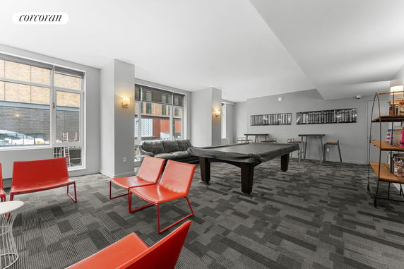 Recreation room with pool table, chairs, and large windows.
