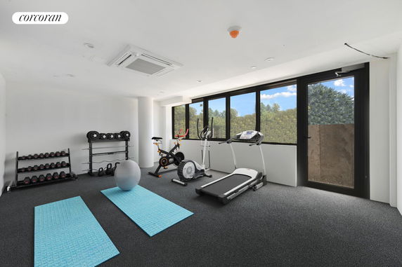 Indoor gym area with exercise equipment and large windows.
