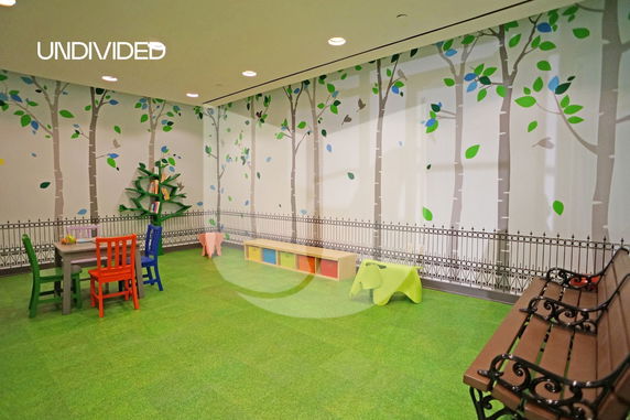 Children's indoor play area with colorful chairs, a table, and decorative wall art.