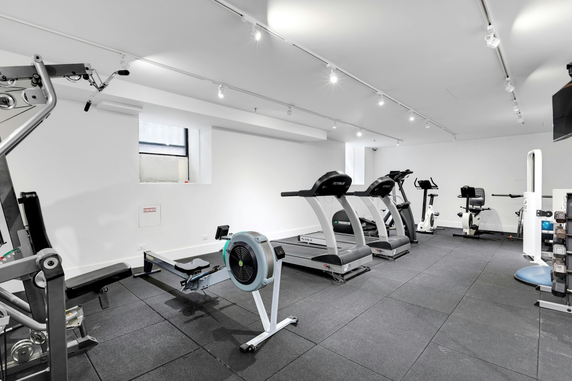 Gym area with exercise equipment including treadmills, stationary bikes, and weights.
