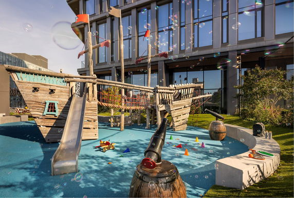Outdoor play area with a pirate-themed wooden structure and slide.