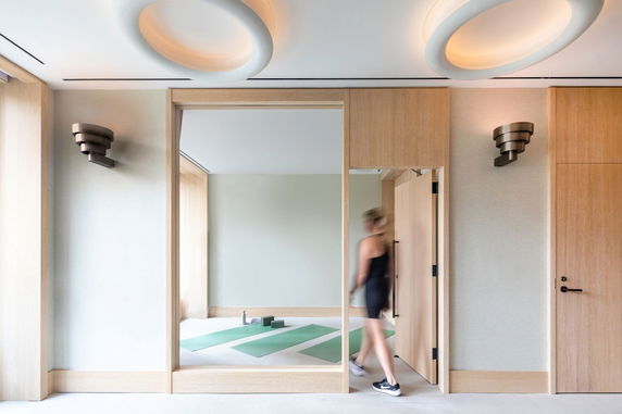 Interior view of a fitness room with yoga mats and modern lighting fixtures.