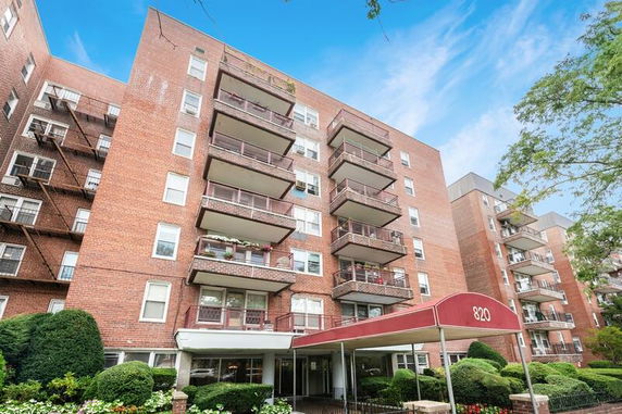 Front view of a multi-story apartment building with balconies and a covered entrance.