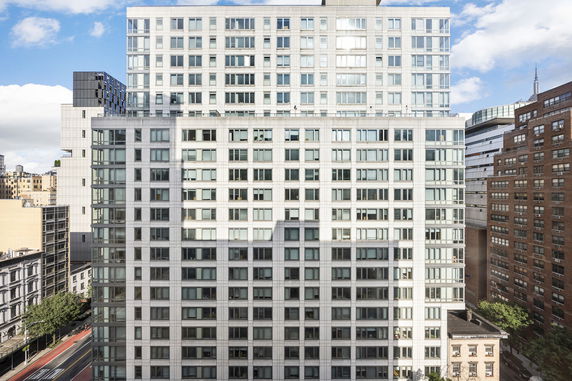 Front view of a tall apartment building with multiple windows.