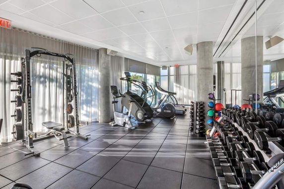 Indoor gym with exercise equipment and weights.