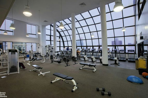 Interior view of a gym with exercise equipment and large windows.