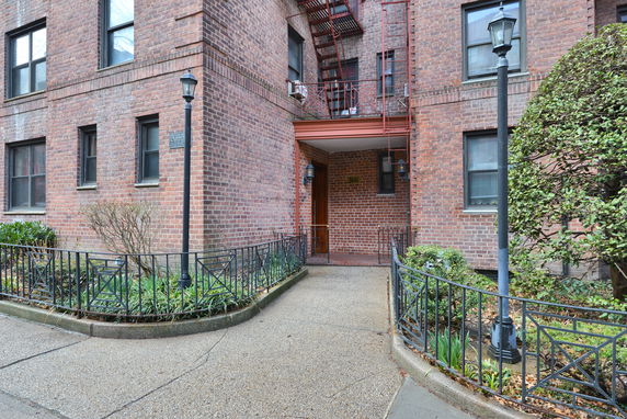 Front view of a brick multi-story building with a walkway and decorative metal fence.