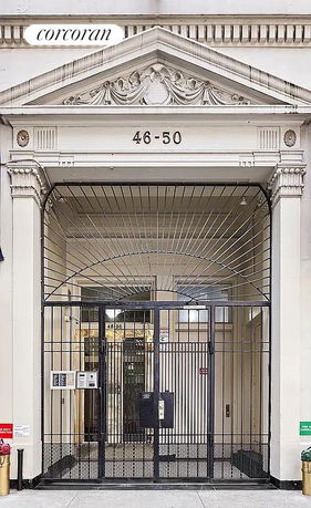 Front view of a building entrance with an ornate pediment and gated entry.