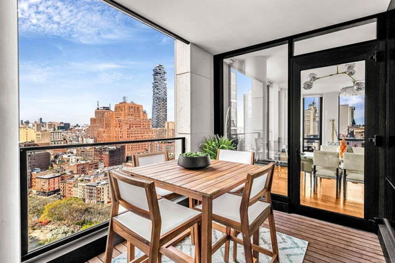 Panoramic cityscape view from a balcony with outdoor furniture.