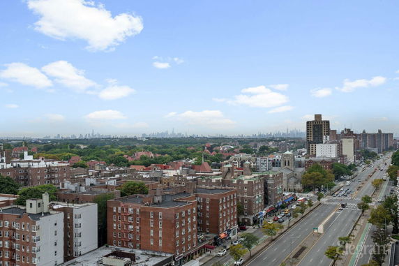 Panoramic view of a cityscape with buildings and roads, and distant skyline on a clear day.