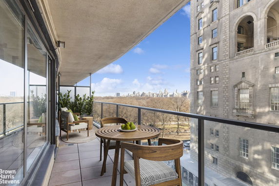 Balcony with outdoor furniture offering a view of a park and city skyline.