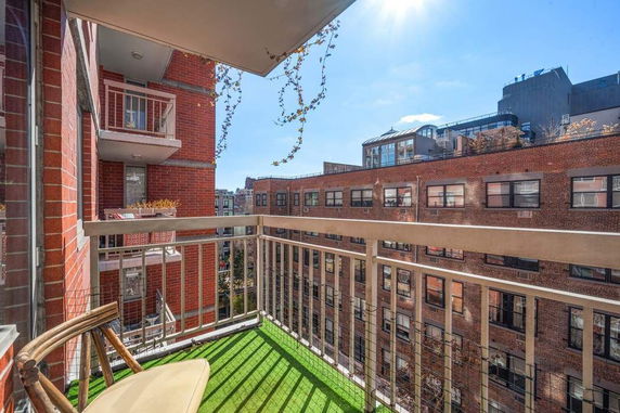 View of a balcony overlooking neighboring buildings under a bright blue sky.