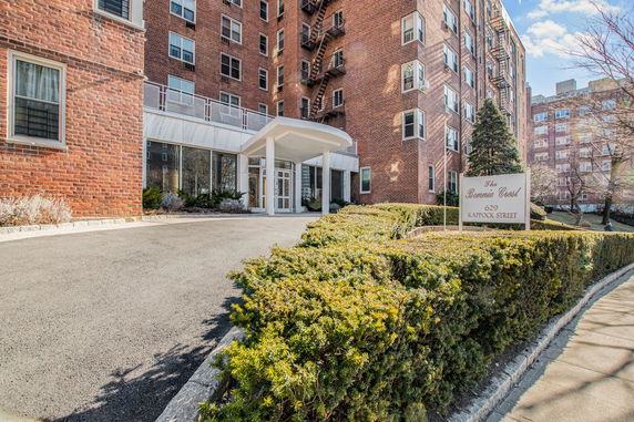 Front view of a multi-story brick apartment building with a covered entrance.
