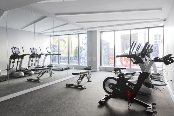 Indoor gym area with exercise equipment and wall mirrors.