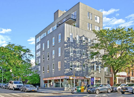 Front view of a multi-story building with retail shops on the ground floor.