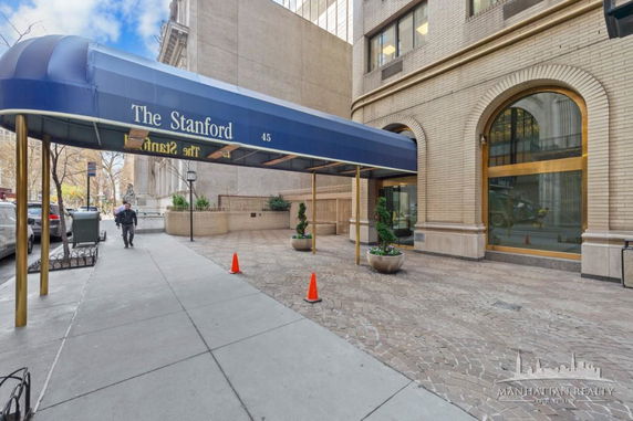 Entrance view of a multi-story brick building with an awning labeled 'The Stanford'.