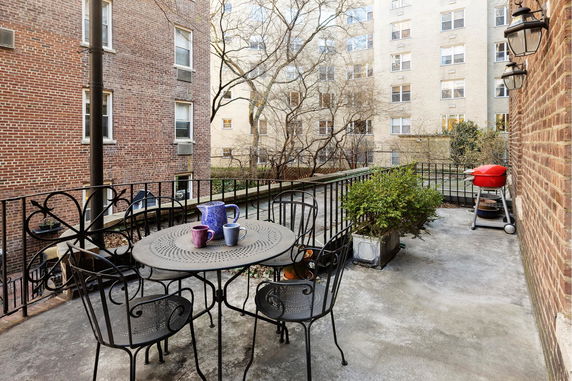 Outdoor terrace with metal furniture and a view of adjacent buildings.