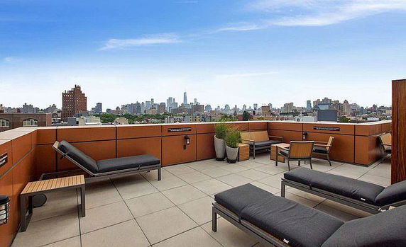 Rooftop seating area with lounge chairs and city skyline view.