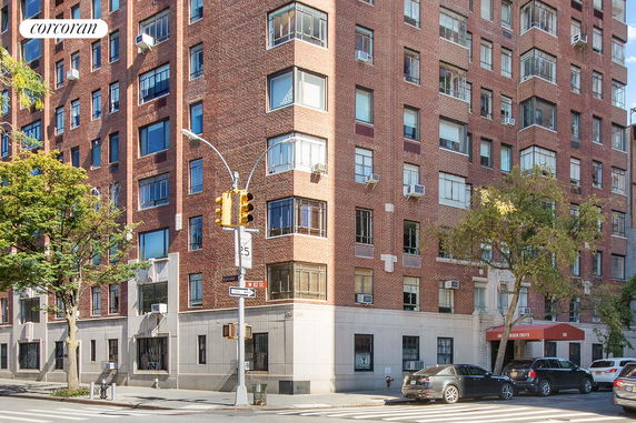 Front view of a multi-story brick apartment building on a city street corner.