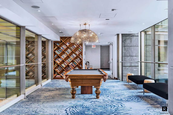 Indoor recreation area with a billiards table and bookcase.