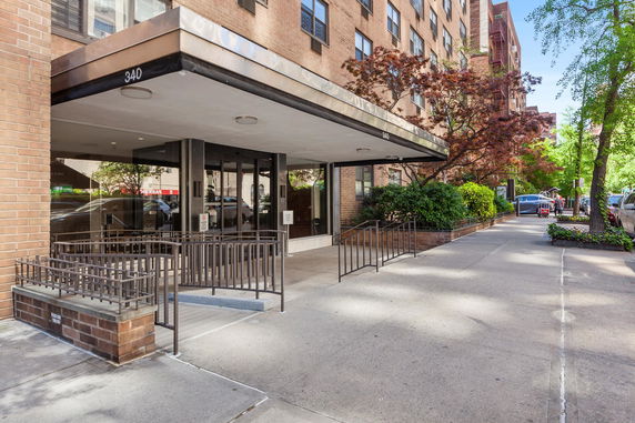 Front view of a multi-story apartment building entrance with a covered walkway.