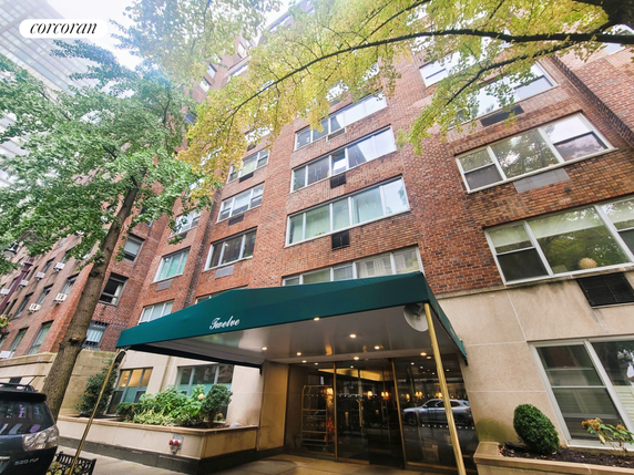 Front view of a multi-story brick apartment building with a green awning over the entrance.