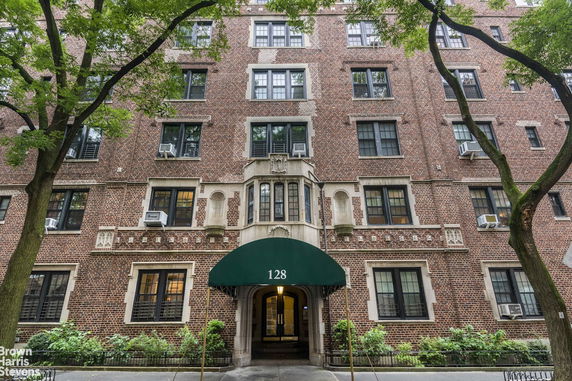 Front view of a multi-story brick apartment building with a green awning at the entrance.