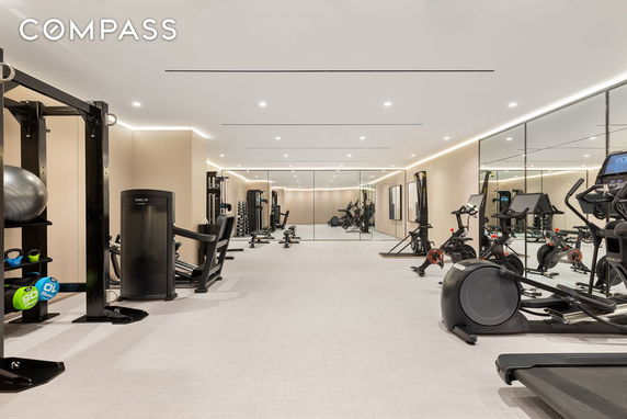 Modern indoor gym area with various exercise equipment and mirrored walls.