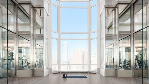 Spacious room with large windows and exercise equipment, featuring a city view.