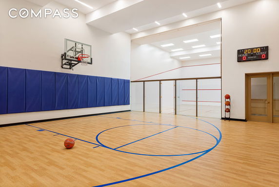 Indoor basketball and squash court with wooden flooring and sports equipment.